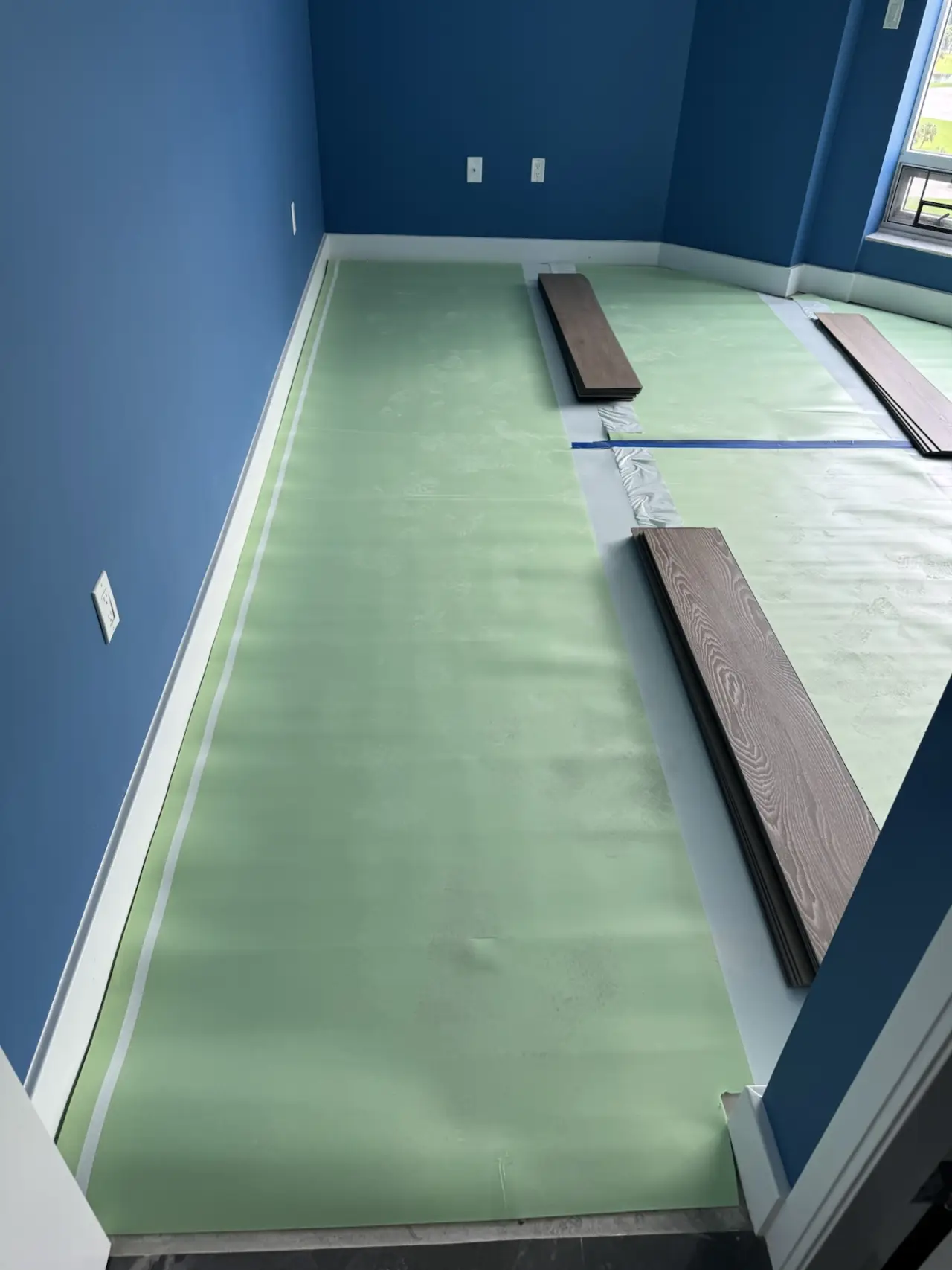 Underlayment · Underlayment rolled out beneath the vinyl, first planks laid out.